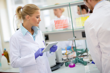 Female chemical technician noting data in laboratory - obrazy, fototapety, plakaty