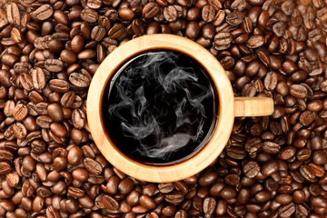 Roasted coffee beans on wood and black coffee in a glass timber.
