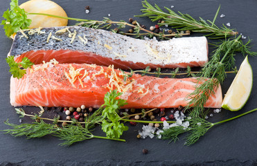 Delicious portion of fresh salmon fillet with aromatic herbs, spices and vegetables - healthy food, diet or cooking concept