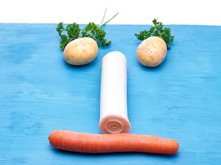 Kartoffeln, Möhren und Petersilie auf blauem Untergrund