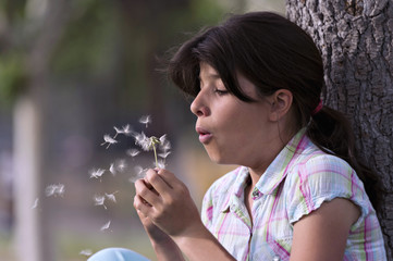 A teenager blowing a dandelion