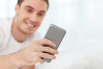 Attractive guy is using telephone in bedroom