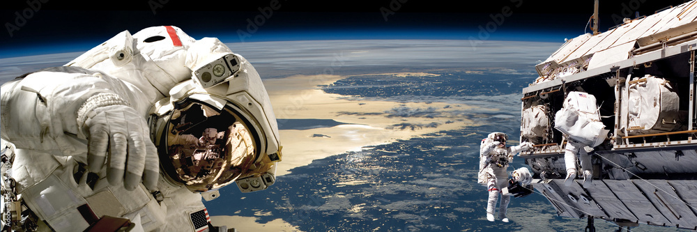 Wall mural a team of astronauts performing work on a space station.- elements of this image furnished by nasa.