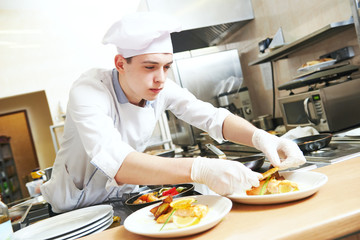 male cook chef decorating food on the plate