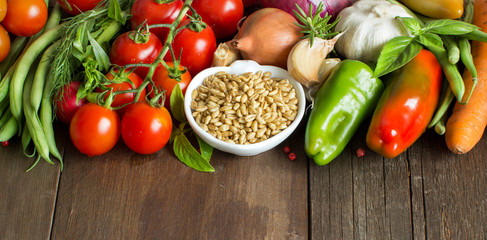 Spelt in a bowl and fresh vegetables