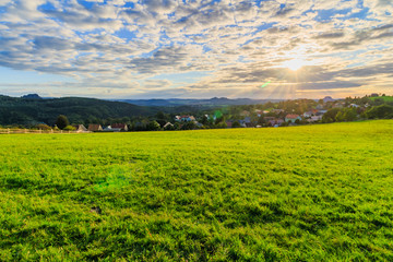 Beautiful sunset over countryside landscape of rolling hills with sun beams piercing sky and lighting hillside