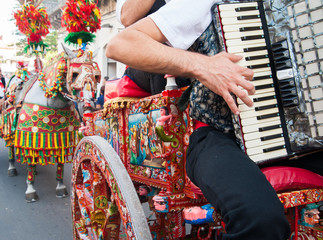 Accordion player wearing a folkloristic dress and playing on a characteristic sicilian cart