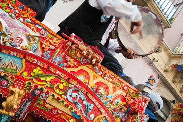 Close up view of a colorful wheel of a typical sicilian cart and a folkloristic tambourine player on it