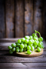 Vine of green grapes on rustic wooden background