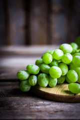 Vine of green grapes on rustic wooden background