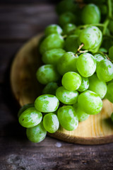 Vine of green grapes on rustic wooden background