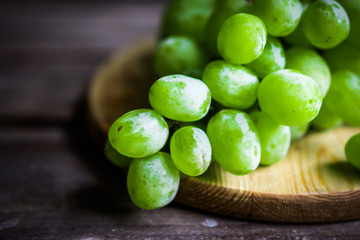 Vine of green grapes on rustic wooden background