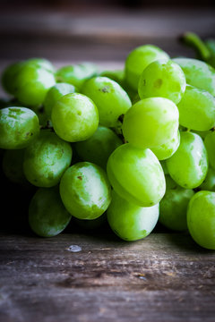 Vine of green grapes on rustic wooden background