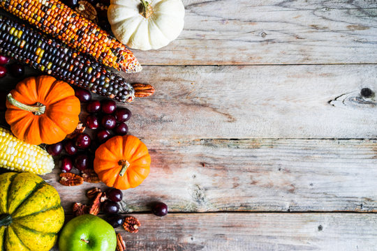 Pumpkins,corn,apples,nuts and cranberries on wooden background