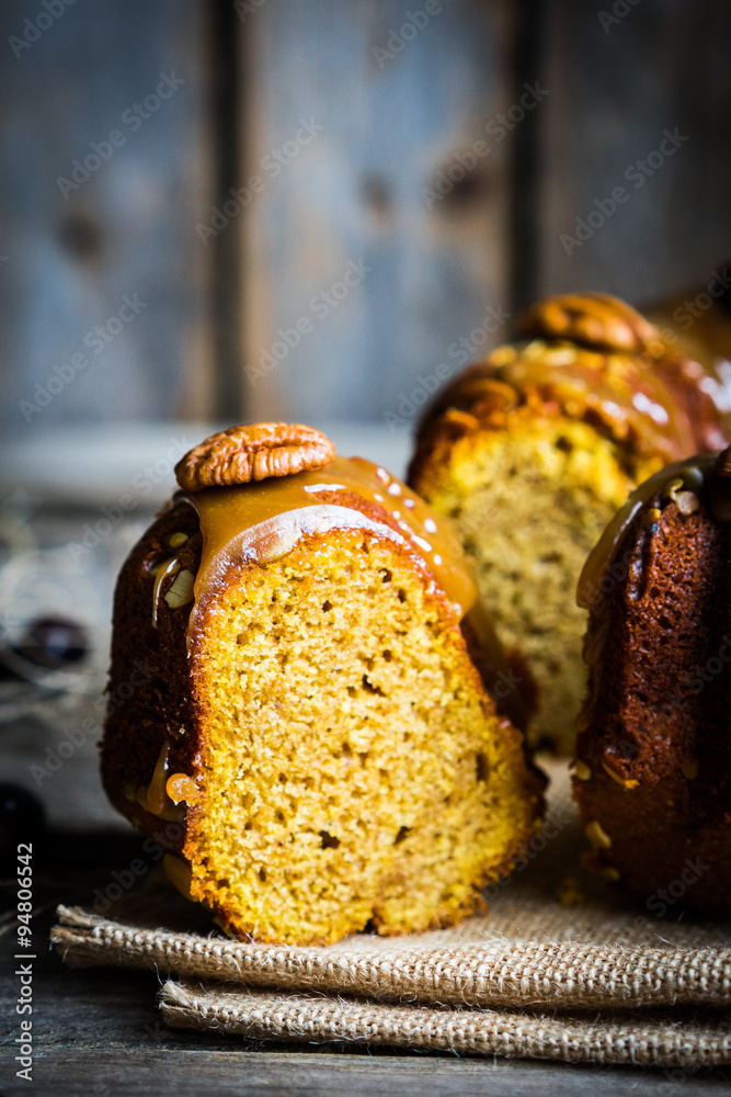 Wall mural Homemade autumn cake with nuts and caramel on wooden background