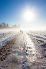 Fototapeta premium Mother and child on foggy snow road