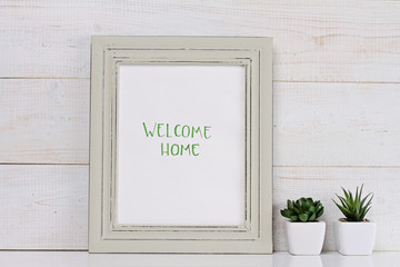 Home and family concept. Welcome home poster in frame rustic , shabby chic, vintage style. Scandinavian style home interior decoration.