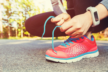Female jogger tying her running shoes for a jog