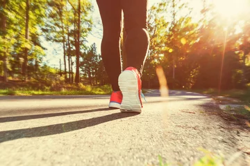 Foto auf Acrylglas Joggen Frau joggt einen Weg im Freien hinunter