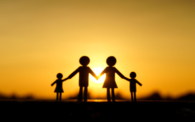 Fototapeta na wymiar Abstract blurred background of paper cut of family with sunset background / Family Life Insurance / Protecting family / Family concepts