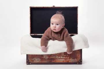 Baby klettert aus Korb mit Kuscheldecke