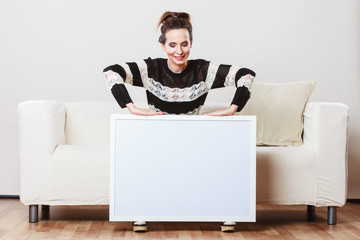 woman on sofa holding blank presentation board.
