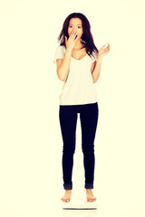 Fototapeta premium Shocked woman standing on a scale.