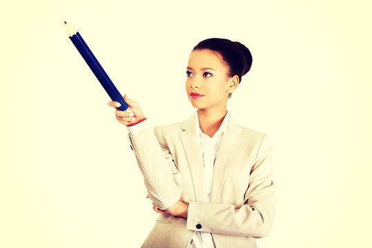 Businesswoman pointing up with big pencil.