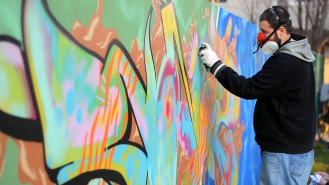 Hip Hop Rap artist with a beard and mask Teenager make graffiti on the wall