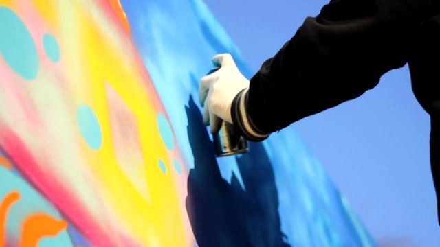Hip Hop Rap artist with a beard and mask Teenager make graffiti on the wall