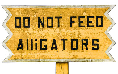 Yellow wooden warning sign with black text. Do not feed Alligators. Vintage board in an alligator farm in Forida Everglades USA warning visitors not to feed animals, yellow background black type - 94820787