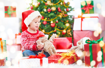 happy child with Christmas gifts near a Christmas tree