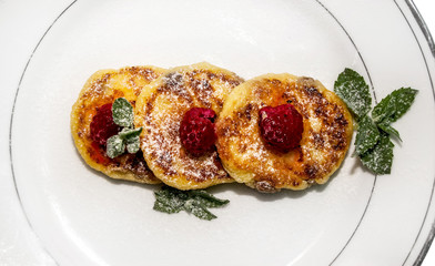cheese fritters with raspberries on a plate isolated on white ba