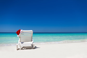 Santa Claus Hat on sunbed near  tropical calm beach with turquoi