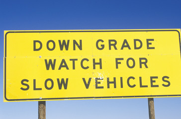 A sign that reads &Ograve;Down grade watch for slow vehicles&Oacute;