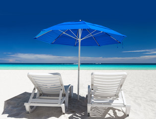 Caribbean beach with blue sun umbrellas and white beds