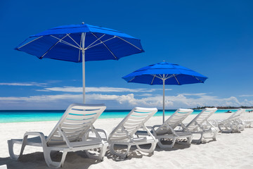 Caribbean beach with blue sun umbrellas and white beds