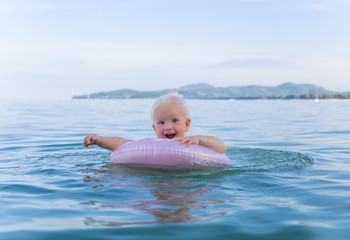 Happy smiling baby girl swimming in the sea. Thailand, Phuket, BangTao beach