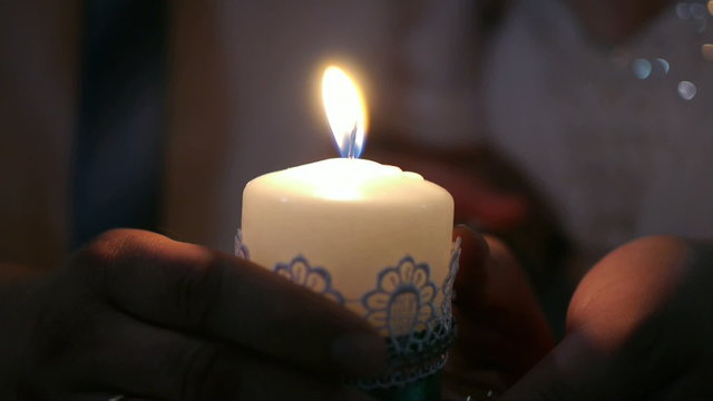 Candle in the hands of the bride and groom