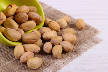 Pistachio nuts in bowl on white wooden table, healthy eating