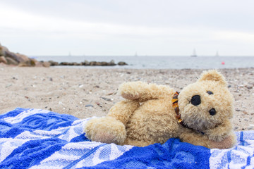  teddy bear / A teddy bear lies on a beach towel on the Baltic beach 