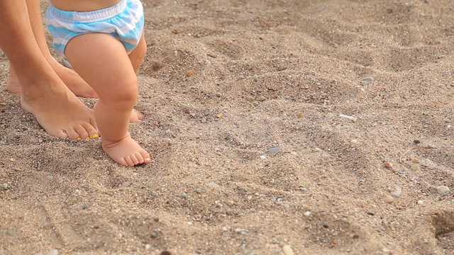 Baby first steps on sea beach, close-up