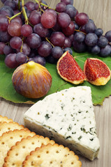 Blue Cheese Accompanied by Figs, Grapes and Saltine Crackers on a Wooden Platter