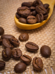 Heap of coffee beans with wooden spoon on jute canvas