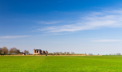 Fototapeta na wymiar Green meadow, blue sky, castle Muiderslot on the horizon