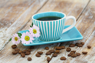 Coffee in vintage cup and pink daisy flowers on rustic wooden surface with copy space
