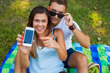 Pretty girl is showing something on smartphone to her boyfriend.