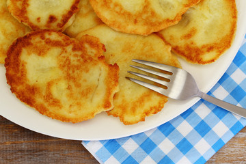Homemade potato fritters on white plate with checkered napkin
