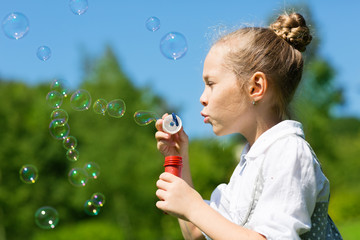 Happy girl blowing soap bubbles
