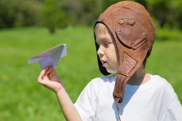 Boy in the old helmet pilot playing with toy plane